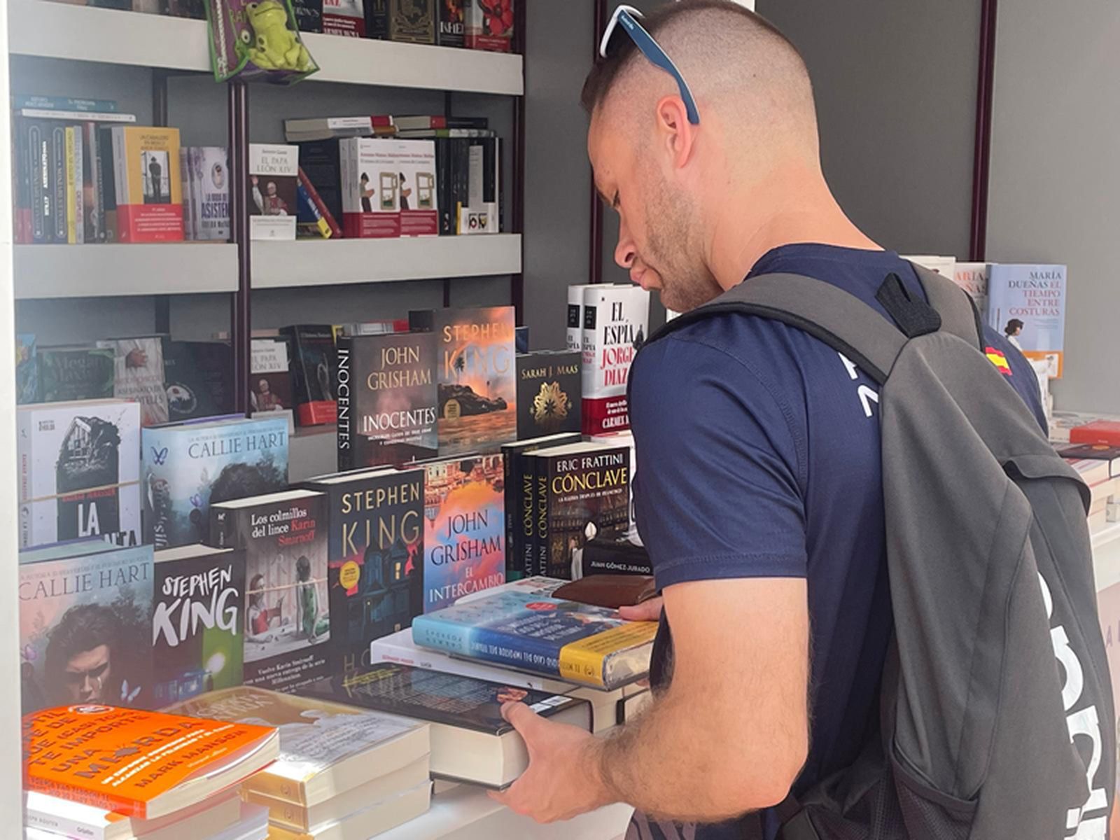 Un lector ojea los libros del puesto de Librería Sol en la Feria del Libro de Ceuta. / FOTO REDUAN