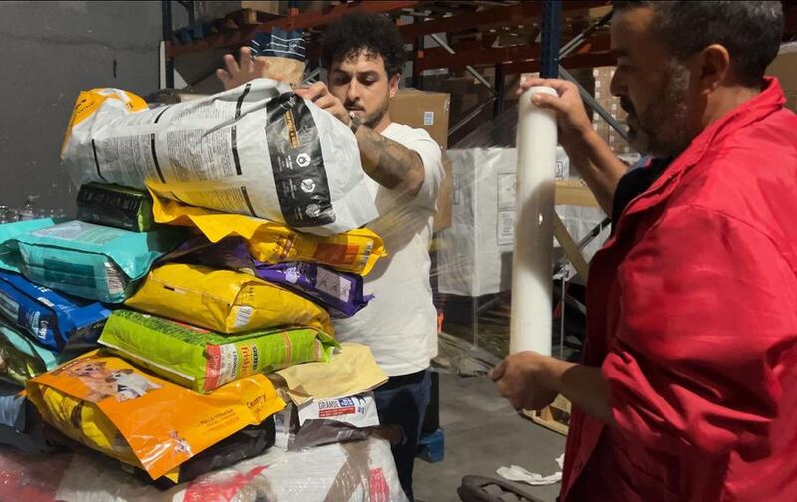 Trabajadores retractilando un palé con pienso para mascotas para Valencia | FOTO E.A.Z.