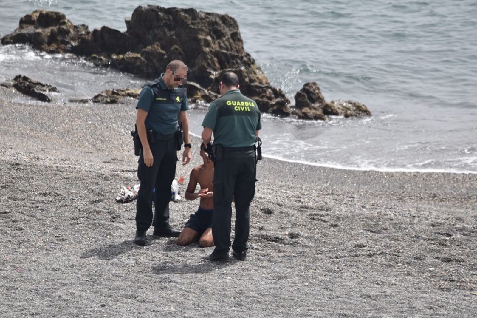 Dos guardias civiles custodian a un menor recién llegado a Ceuta/ FOTO NICOL'S